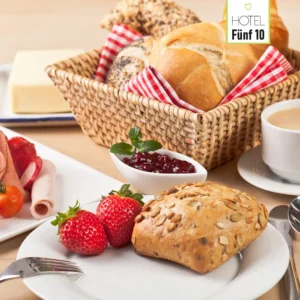 Frühstückstisch mit Brötchenkorb, Erdbeeren, Aufschnitt und Kaffee im Hotel Fünf10.